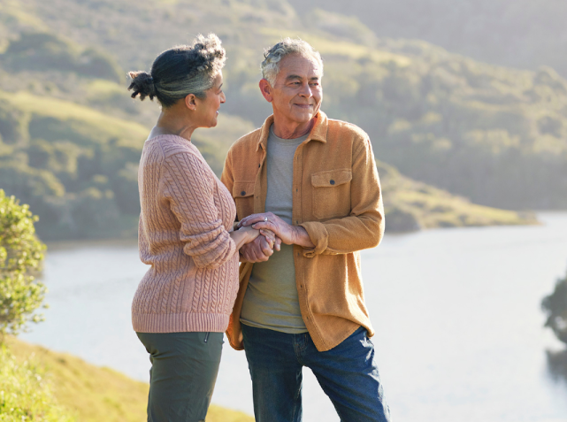 A man and woman hold hands in front of lake