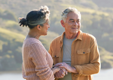 A man and woman hold hands in front of lake